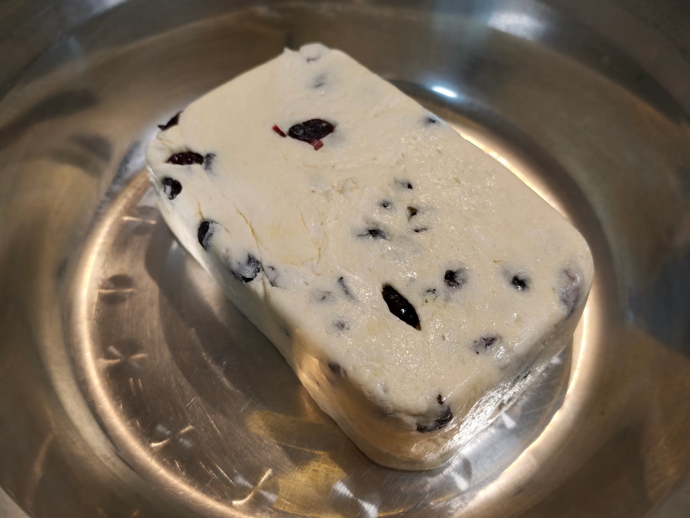 A slab of cranberry nougat in a steel bowl