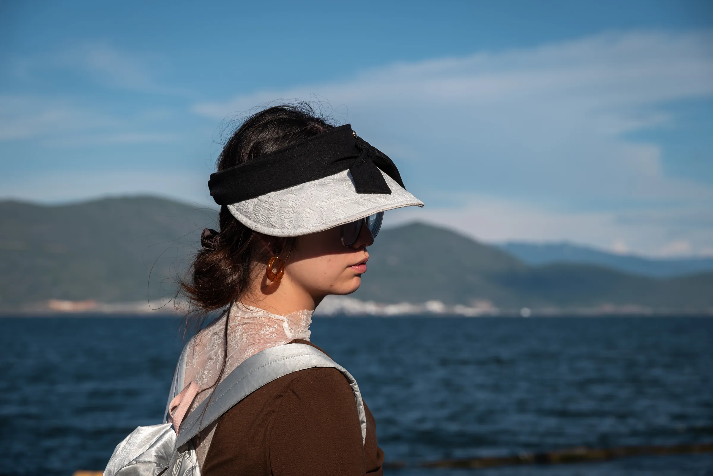 A woman in a sun visor looking out over Erhai Lake