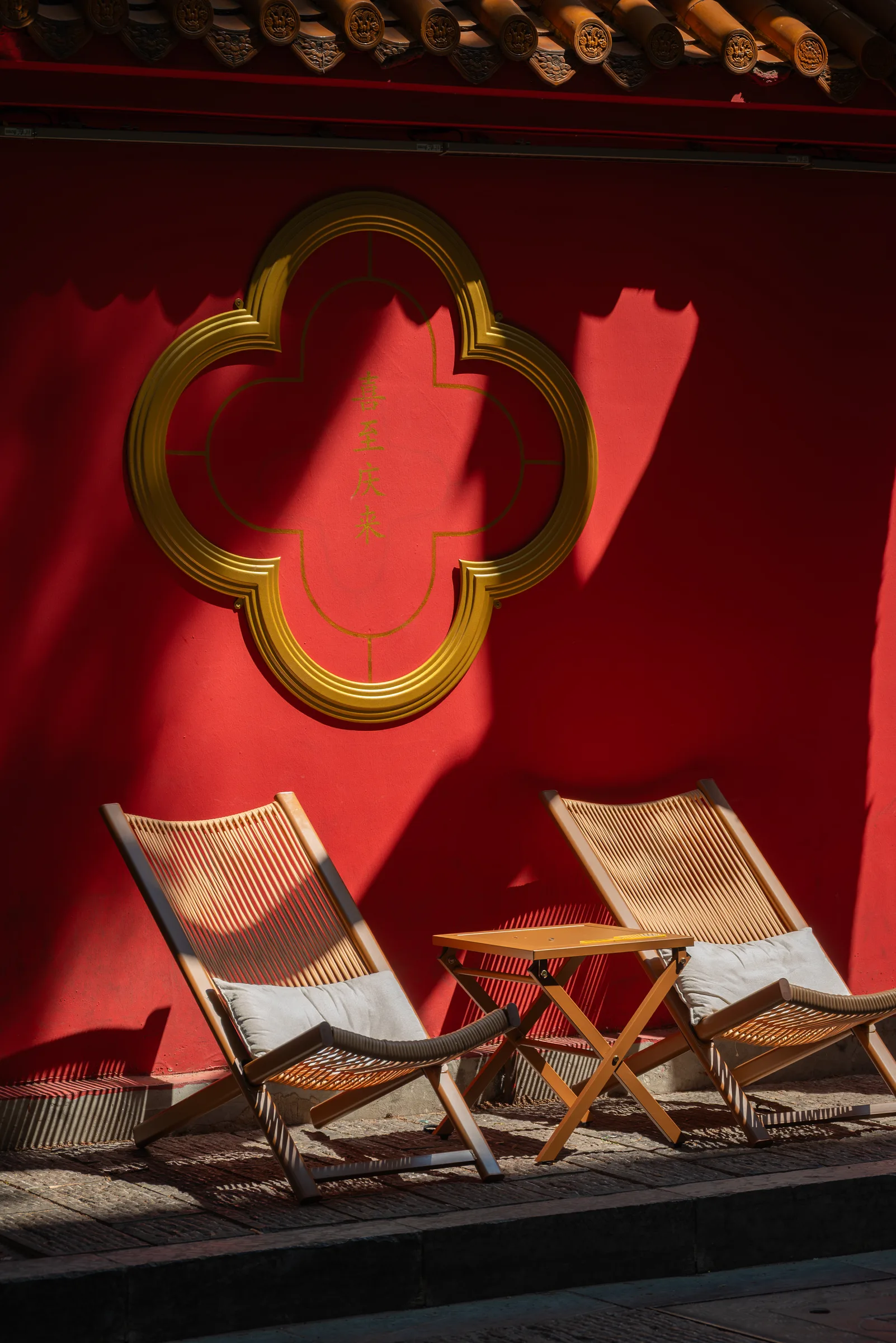 Two folding chairs in front of a red wall with a golden window