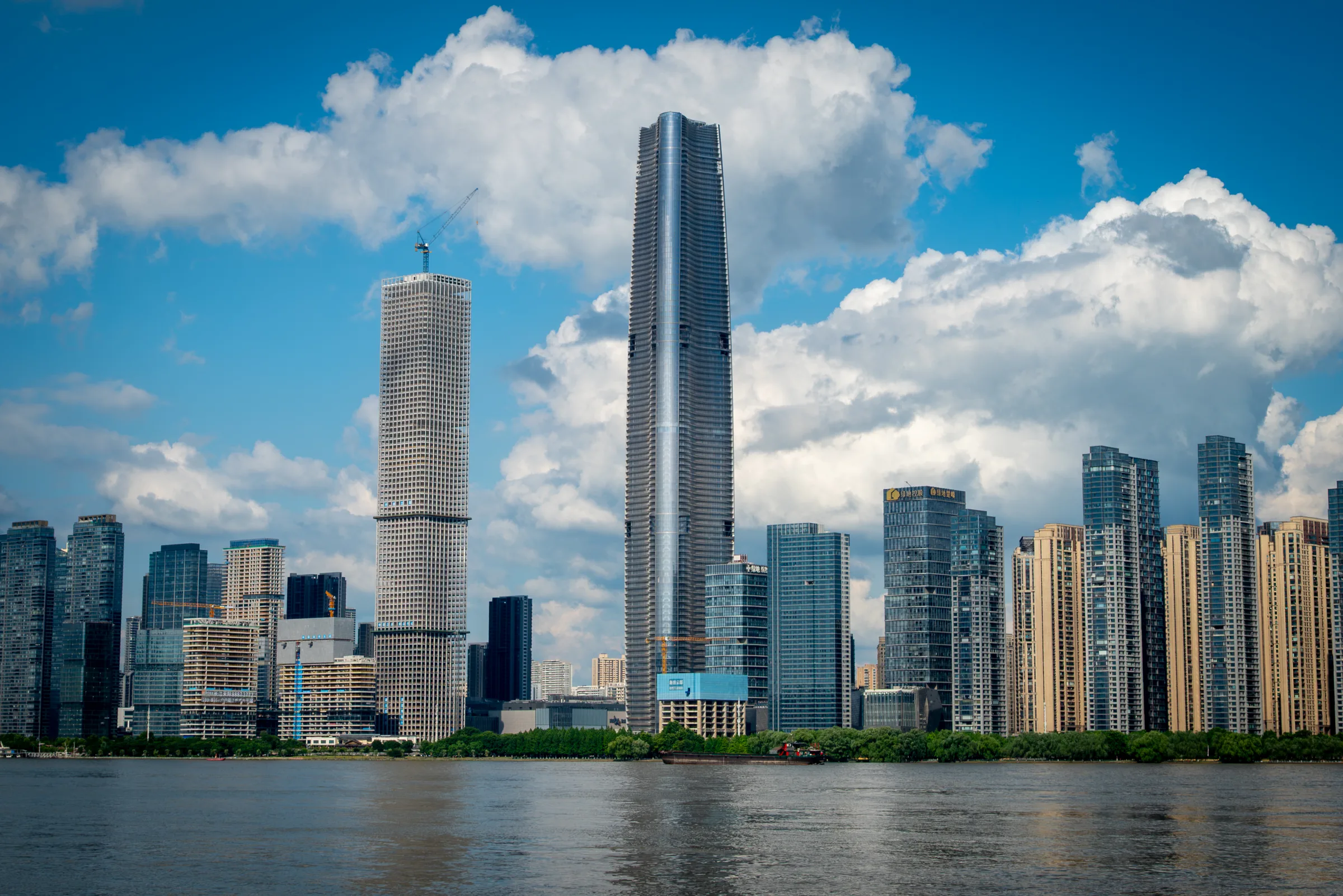 Two towers under construction with cranes against clouds