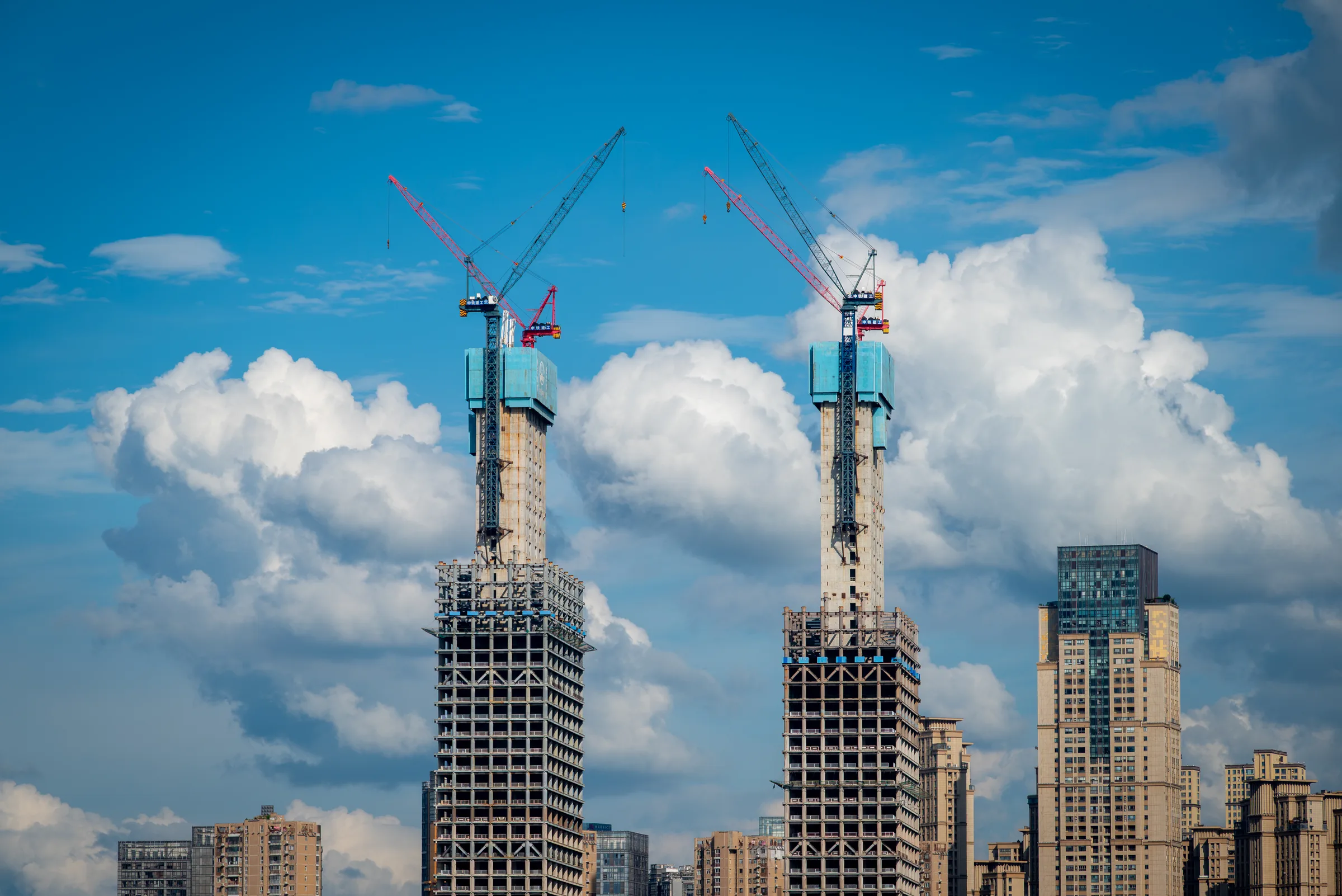 A tower under construction beside a finished skyscraper